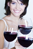 Drei Gläser Rotwein, im Hintergrund junge Frau