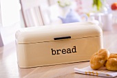 Bread bin and bread rolls on breakfast table
