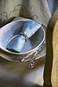 Place-setting with blue fabric napkin and silver cutlery
