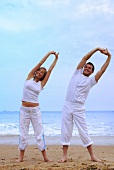 Man and woman doing exercises on beach