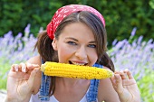 Young woman eating grilled corn on the cob