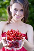 Young woman holding a plastic punnet of redcurrants