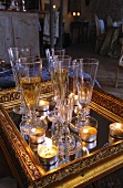 Glasses of sparkling wine and tealights on mirror