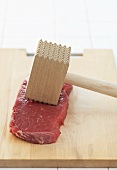 Beef with meat mallet on chopping board