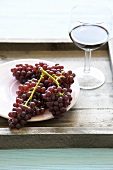 Red grapes and a glass of red wine on a tray