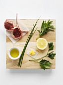 Ingredients for lamb chops with herbs on chopping board (overhead)