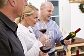 A woman and two men tasting red wine