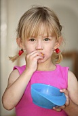 Girl eating potato crisps out of a blue bowl