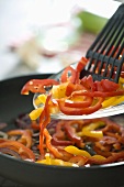 Frying sliced peppers in a frying pan