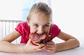 Girl eating an open ham sandwich