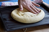 Flattening yeast dough on a baking tray