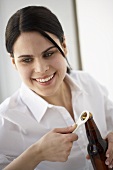 Frau öffnet eine braune Bierflasche