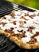 Pizza topped with ham, figs and goat's cheese on barbecue