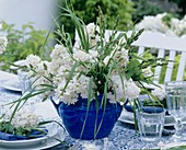 Blau-weiße Tischdekoration mit Flieder und Gräsern