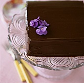 Square chocolate cake decorated with purple flowers