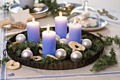 Juniper sprigs with tree ornaments & four candles in baking tin