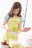 Girl sieving flour into a bowl