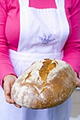 Frau hält selbst gebackenes Brot