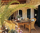 Laid wooden table with rattan armchairs on a veranda