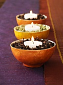 Three bowls of spices with candles