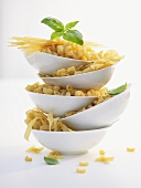 Various types of pasta in five dishes, basil leaves
