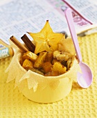Exotic fruit salad with cinnamon sticks in brik pastry shell