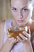 Young woman drinking chamomile tea