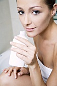 Young woman with body lotion in her hand