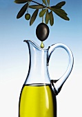 Olive oil dripping from an olive into a carafe