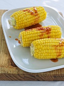 Cooked corn on the cob with chilli sauce