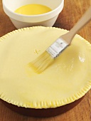 Brushing a pie crust with egg yolk