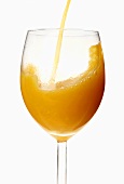 Ein Glas Orangensaft einschenken