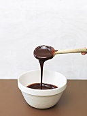 Home-made chocolate sauce running from a wooden spoon