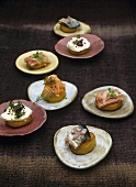 Potato canapes with meat in aspic, salmon, herring and goat's cheese