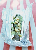 Salmon trout with slices of limes and butter on a sheet of aluminium foil