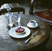Raspberry tart, a cup of coffee and a glass of water