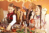 Vier Kinder als Cowboys und Indianer verkleidet am Büffet auf Faschingsparty