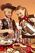 Two children at a party buffet pouring tea