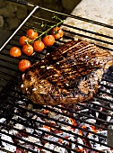 Grilled beef steak with cherry tomatoes on a barbeque