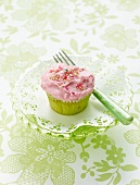 A pink cupcake on a doily