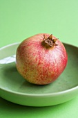 A pomegranate on a green plate