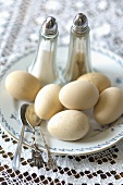 A plate of boiled eggs with salt and pepper shakers