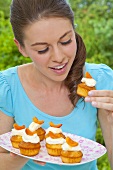 A young woman eating an apricot muffin