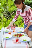 A girl serving a tomato and rocket salad in the open air