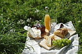 A picnic with ham, butter, ciabatta, grapes and juice