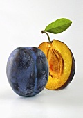Whole and halved damsons with a leaf