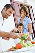 Family with daughter preparing salad out of doors