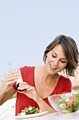 Young woman seasoning her salad out of doors