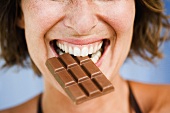 Young woman biting into a chocolate bar