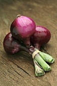 Three red onions on wooden background